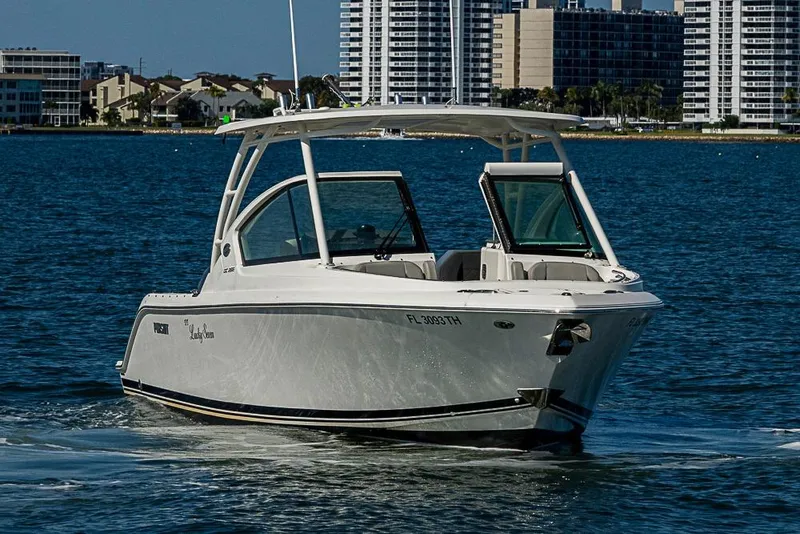 Slide: The Image of 2022 Pursuit DC 266 Dual Console boat cruising on water near city skyline. - 20