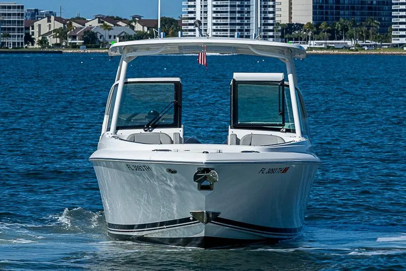 Slide: The Image of 2022 Pursuit DC 266 Dual Console boat cruising on blue water near cityscape. - 21