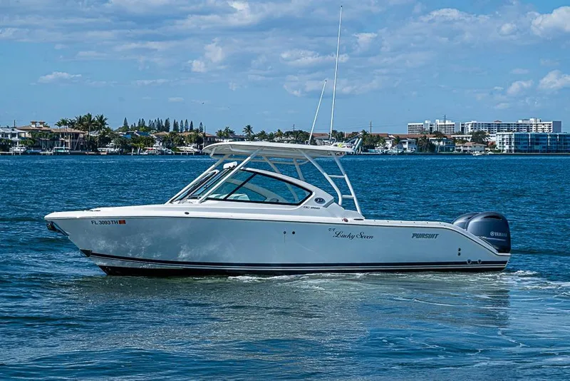 Slide: The Image of 2022 Pursuit DC 266 Dual Console boat cruising on a sunny day near coastal buildings. - 23