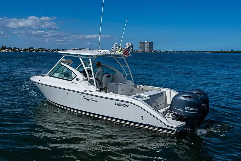 Slide: The Image of 2022 Pursuit DC 266 Dual Console boat cruising on open water under clear skies. - 27