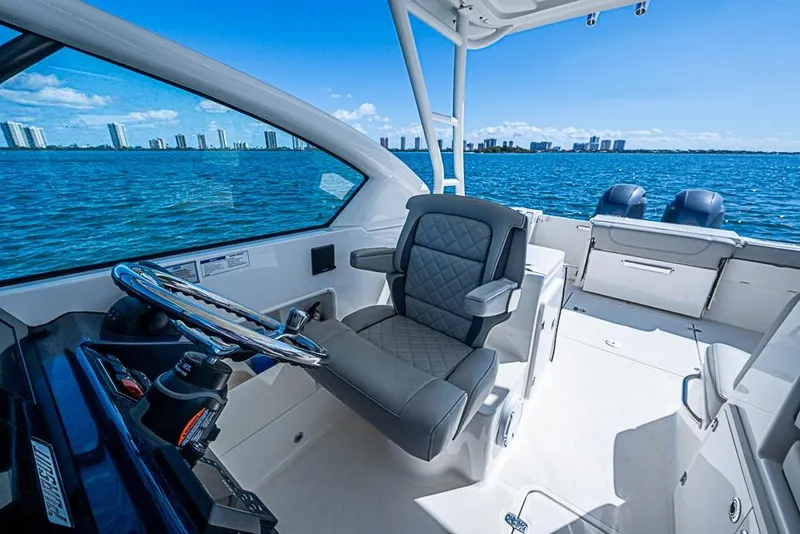 Slide: The Image of 2022 Pursuit DC 266 Dual Console boat interior with steering wheel, luxurious seating, and ocean view. - 35
