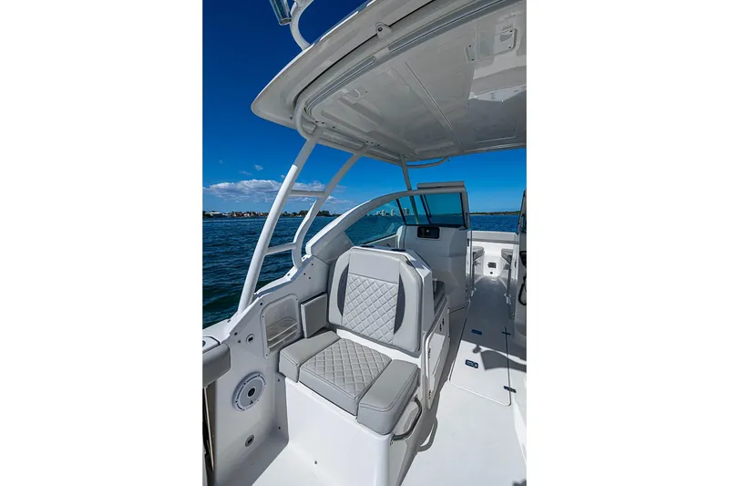 Slide: The Image of 2022 Pursuit DC 266 Dual Console boat interior with cushioned seating on a sunny day. - 7