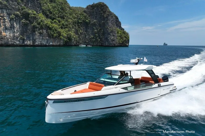 Slide: The Image of 2023 Saxdor 320 GTO cruising in clear blue waters near rocky cliffs. - 0