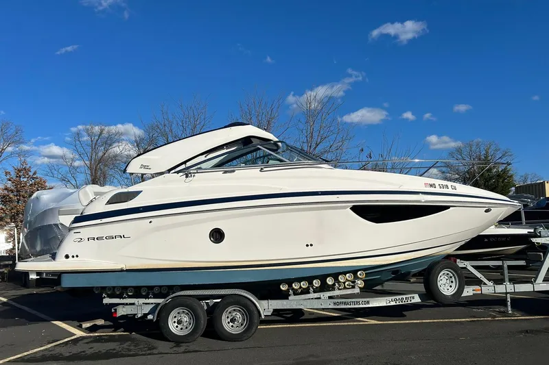 Slide: The Image of 2024 Regal 28 Express boat on trailer under clear blue sky. - 3