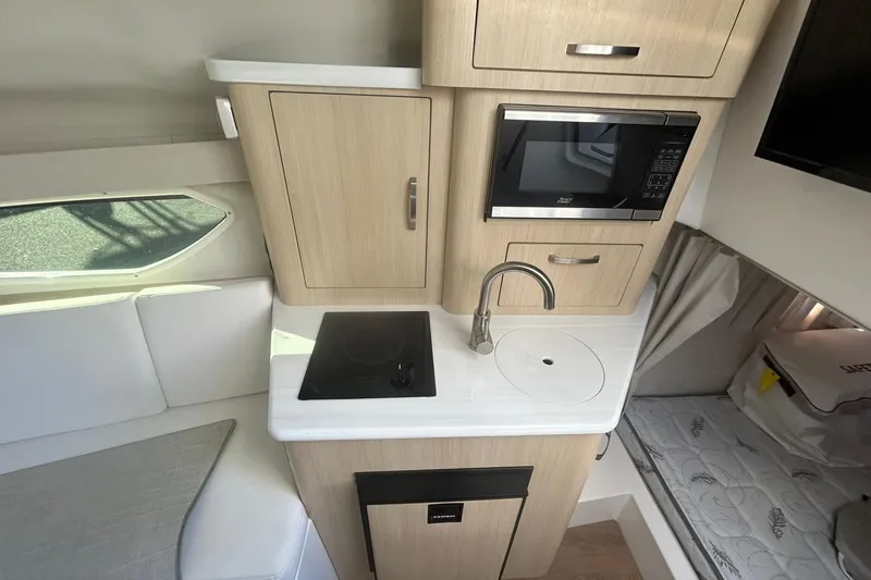 Slide: The Image of 2024 Regal 28 Express boat interior with kitchenette, featuring microwave, sink, and stove. - 45