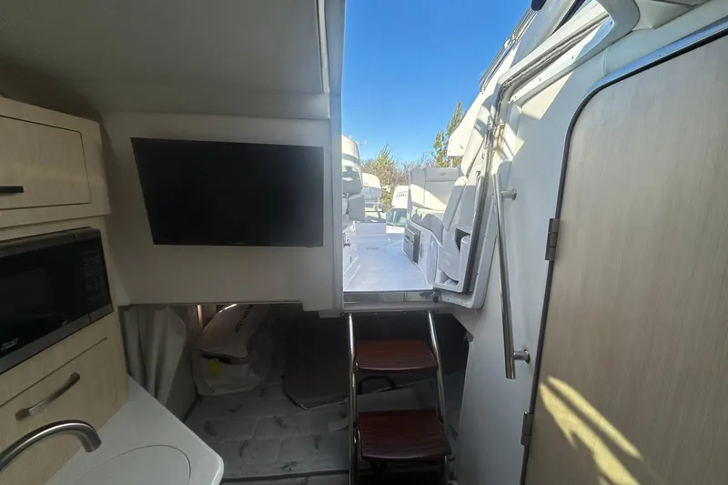 Slide: The Image of Interior of 2024 Regal 28 Express boat with TV, kitchenette, and outdoor access. - 47