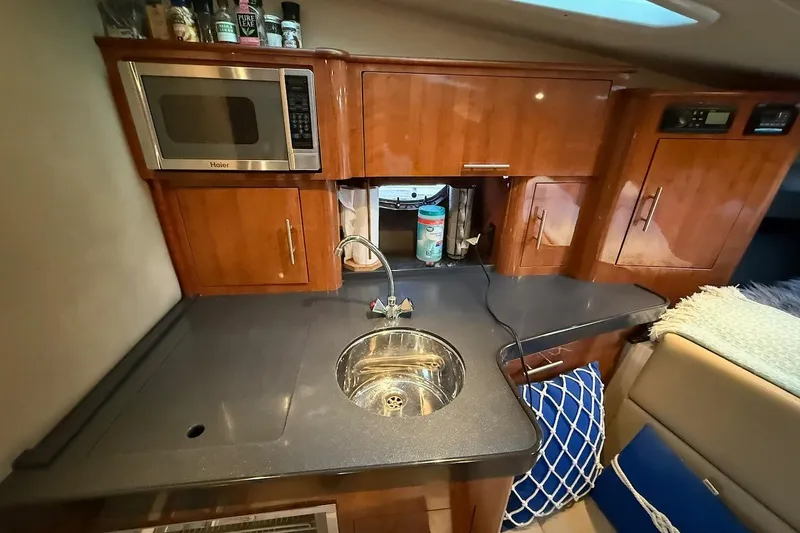 Slide: The Image of 2012 Regal 35 Sport Coupe kitchen with microwave, sink, and wooden cabinets. - 17