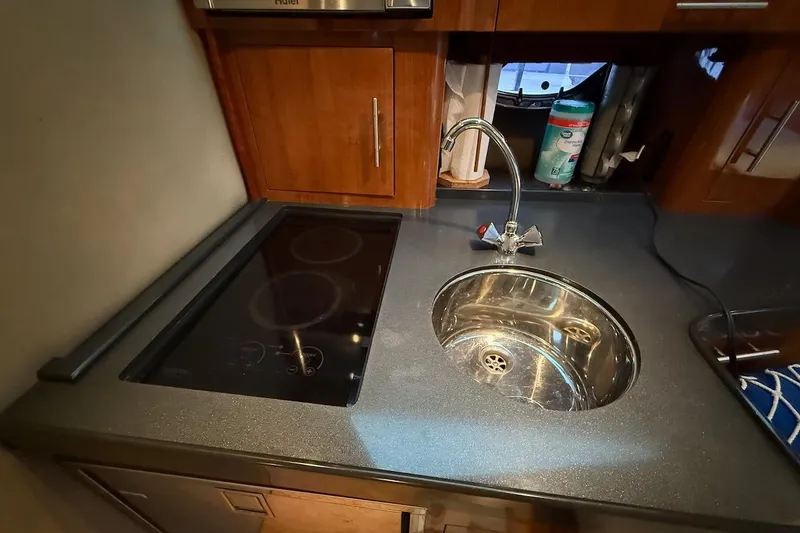 Slide: The Image of Compact kitchen area in a 2012 Regal 35 Sport Coupe with sink and stovetop. - 18