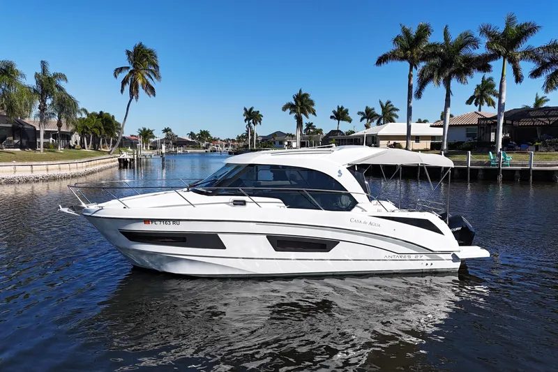 Slide: The Image of 2019 Beneteau Antares 27 boat on a sunny canal with palm trees. - 6