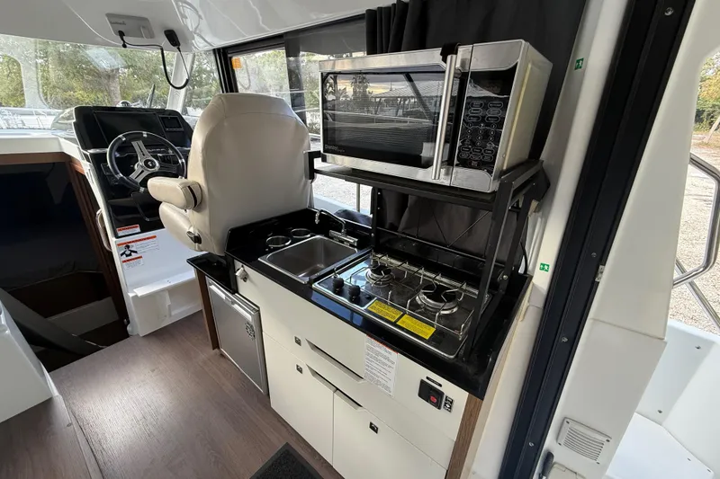 Slide: The Image of Interior of 2019 Beneteau Antares 27 featuring kitchen and helm station. - 7