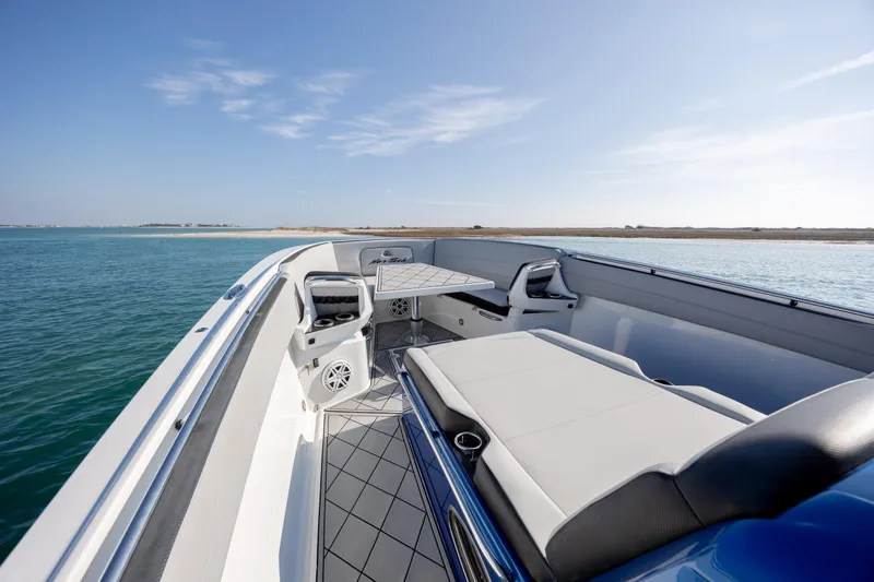 Slide: The Image of 2020 Nor-Tech 390 Sport Center Console boat interior with seating and table on calm water. - 13