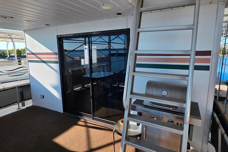 Slide: The Image of 1999 Stardust Cruisers 16x60 houseboat deck with grill and ladder, featuring sliding glass doors. - 12