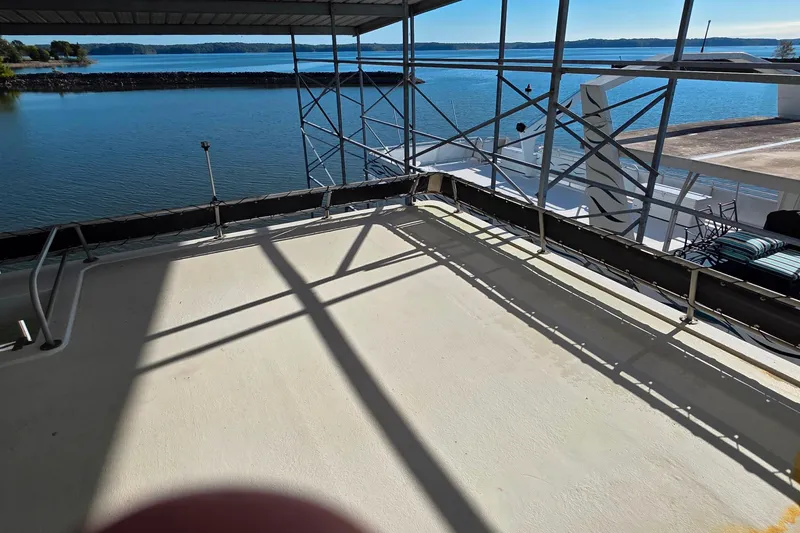 Slide: The Image of 1999 Stardust Cruisers 16x60 houseboat deck with scenic lake view and metal railings. - 18