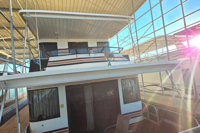 Slide: The Image of 1999 Stardust Cruisers 16x60 houseboat docked under a sunlit canopy. - 25