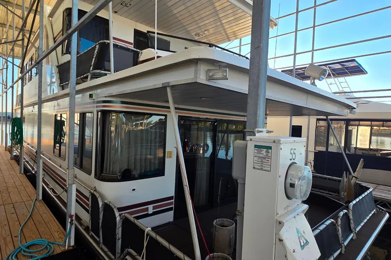 Slide: The Image of 1999 Stardust Cruisers 16x60 houseboat docked in a marina, featuring a spacious deck. - 27