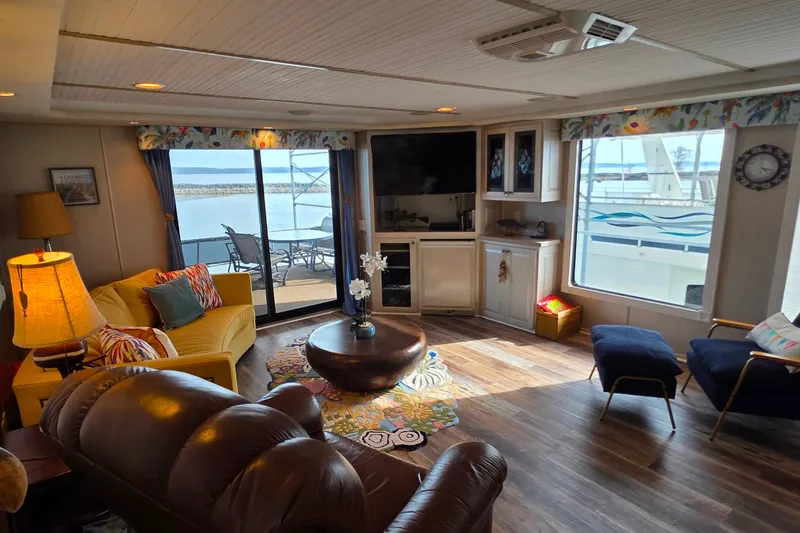 Slide: The Image of Cozy 1999 Stardust Cruisers 16x60 houseboat interior with lake view, featuring comfortable seating and decor. - 35