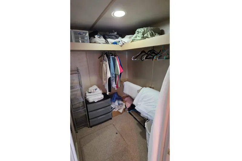 Slide: The Image of 1999 Stardust Cruisers 16x60 houseboat closet with clothes, storage bins, and bedding. - 60