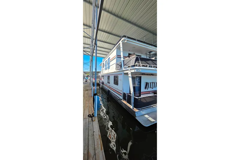 Slide: The Image of 1999 Stardust Cruisers 16x60 houseboat docked under a covered marina. - 7