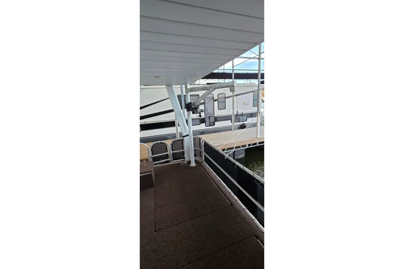 Slide: The Image of 1999 Stardust Cruisers 16x60 houseboat docked, featuring covered deck and railing. - 78