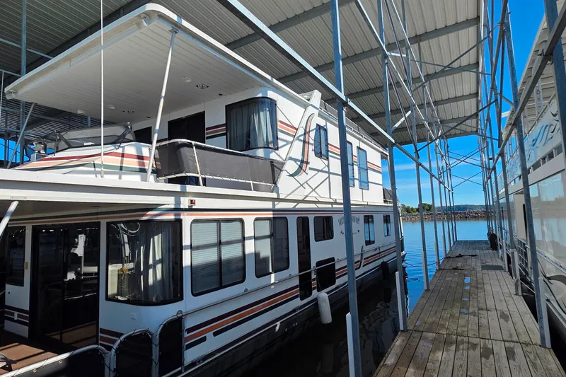 Slide: The Image of 1999 Stardust Cruisers 16x60 houseboat docked under a metal canopy on a sunny day. - 9