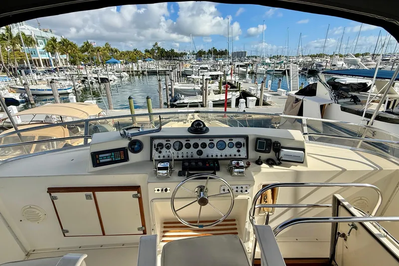 Slide: The Image of 1987 Chris-Craft 500 Constellation yacht helm with marina view, featuring control panel and steering wheel. - 25