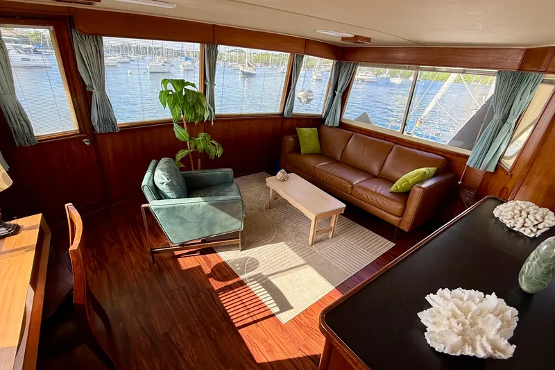 Slide: The Image of 1987 Chris-Craft 500 Constellation yacht interior with leather sofa, armchair, and scenic marina view. - 27