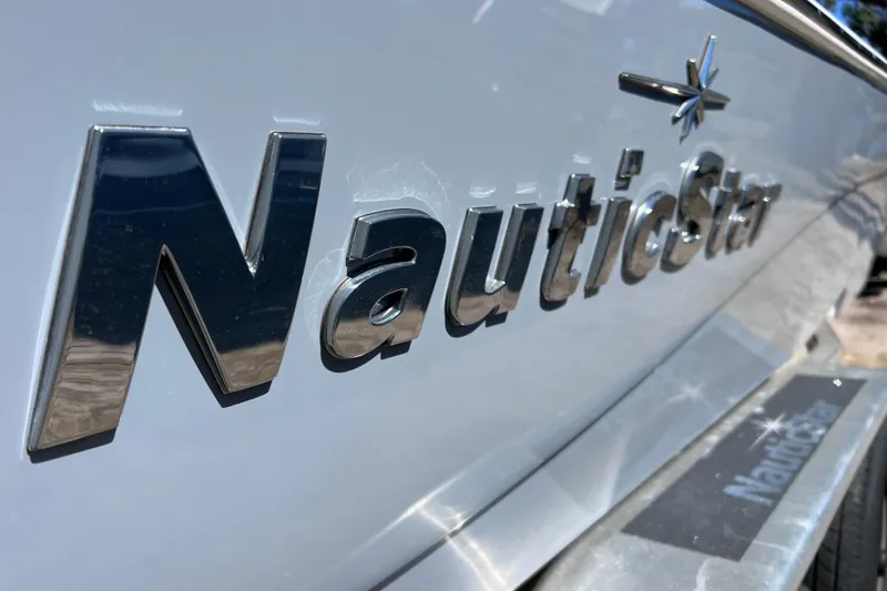 Slide: The Image of 2021 NauticStar 227 XTS boat logo in shiny chrome lettering on hull. - 13