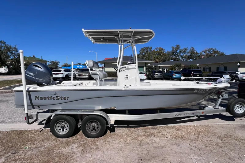 Slide: The Image of 2021 NauticStar 227 XTS boat on trailer, parked outdoors under clear blue sky. - 14