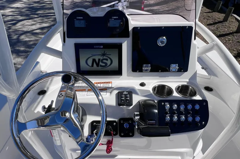 Slide: The Image of 2021 NauticStar 227 XTS boat dashboard with steering wheel, controls, and Simrad display. - 31