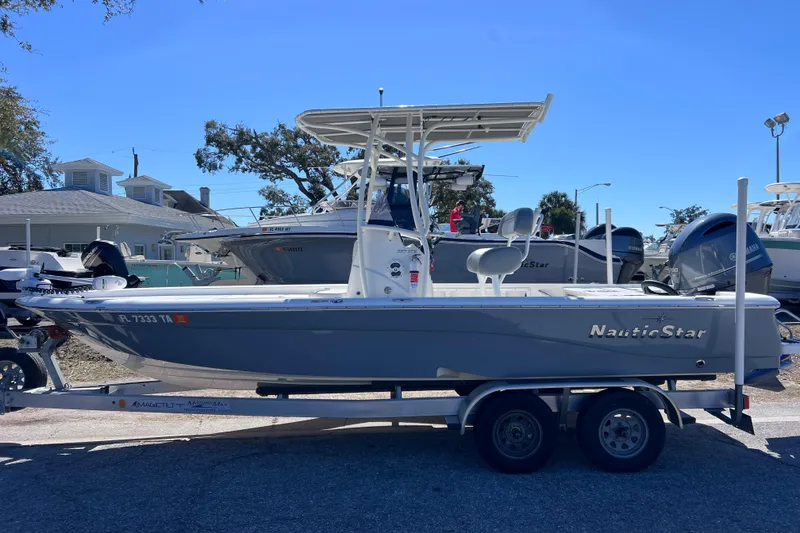 Slide: The Image of 2021 NauticStar 227 XTS boat on trailer, parked outdoors under clear blue sky. - 4