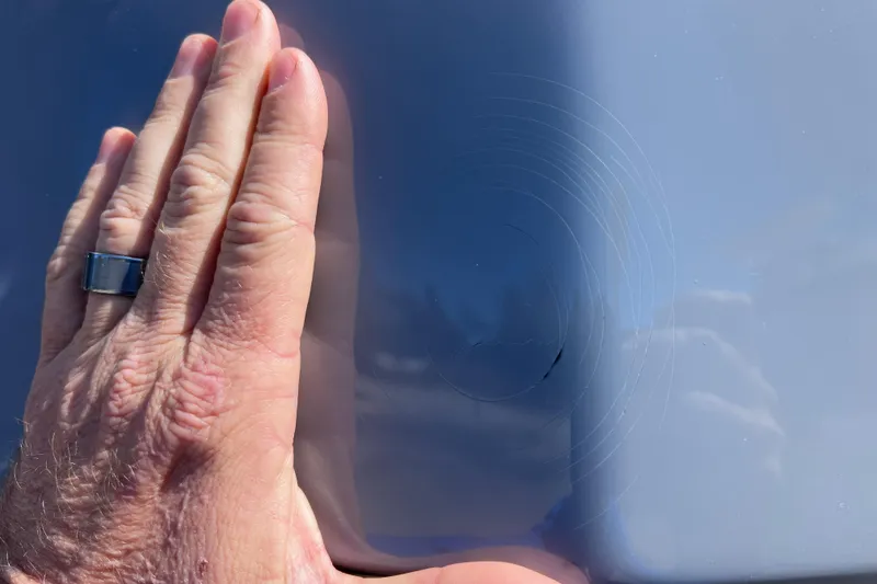 Slide: The Image of Hand inspecting scratch on 2021 NauticStar 227 XTS boat hull. - 60
