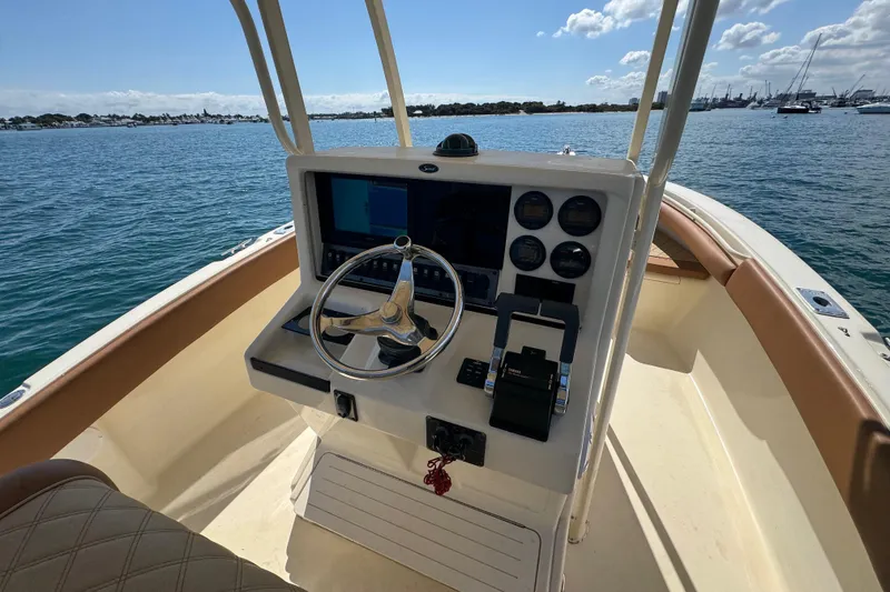 Slide: The Image of 2004 Scout 280 Sportfish boat dashboard with steering wheel and controls on open water. - 22