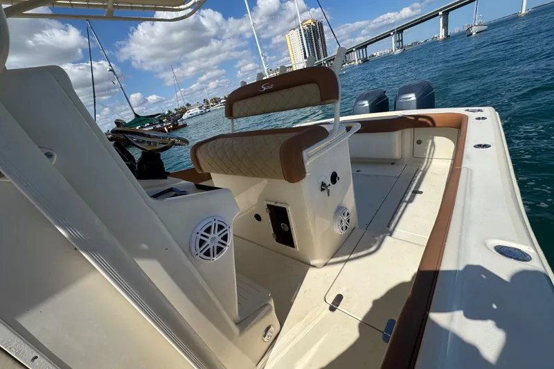 Slide: The Image of 2004 Scout 280 Sportfish boat interior with seating, ocean view, and bridge in background. - 26