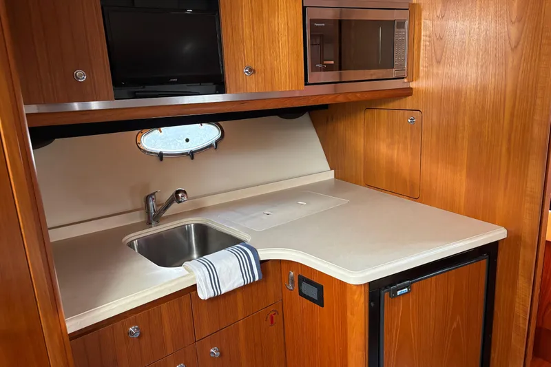 Slide: The Image of 2005 Tiara Yachts 3600 Open galley with sink, microwave, and wooden cabinetry. - 17