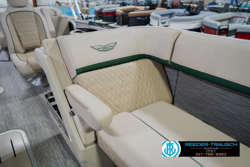 Slide: The Image of 2026 Bennington 24 MFB boat interior with beige quilted seating and green accents. - 24