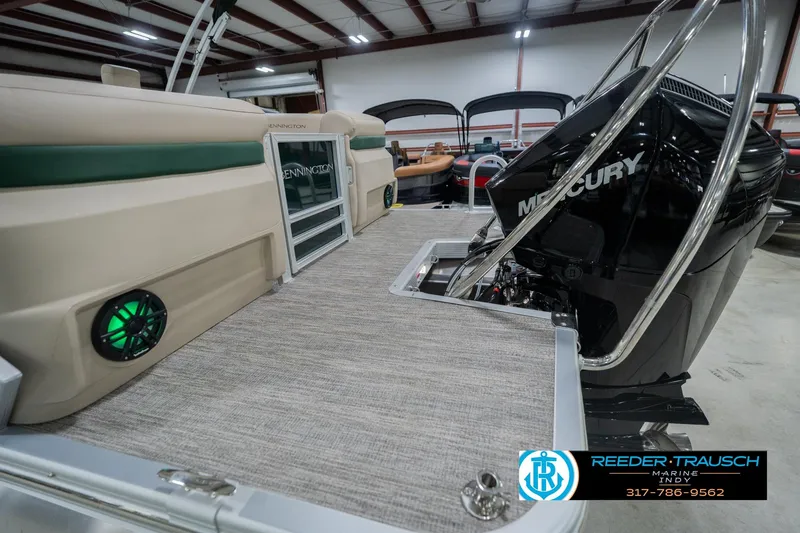 Slide: The Image of 2026 Bennington 24 MFB boat with Mercury engine in showroom, featuring green LED speakers. - 60