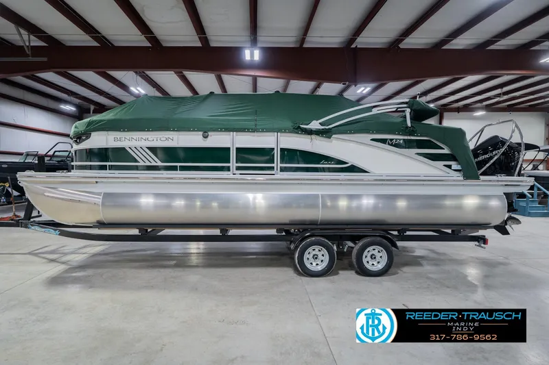 Slide: The Image of 2026 Bennington 24 MFB pontoon boat with green cover on trailer in showroom. - 61