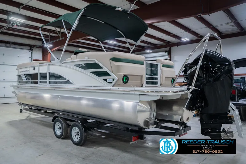 Slide: The Image of 2026 Bennington 24 MFB pontoon boat in showroom, featuring a Mercury outboard motor. - 9