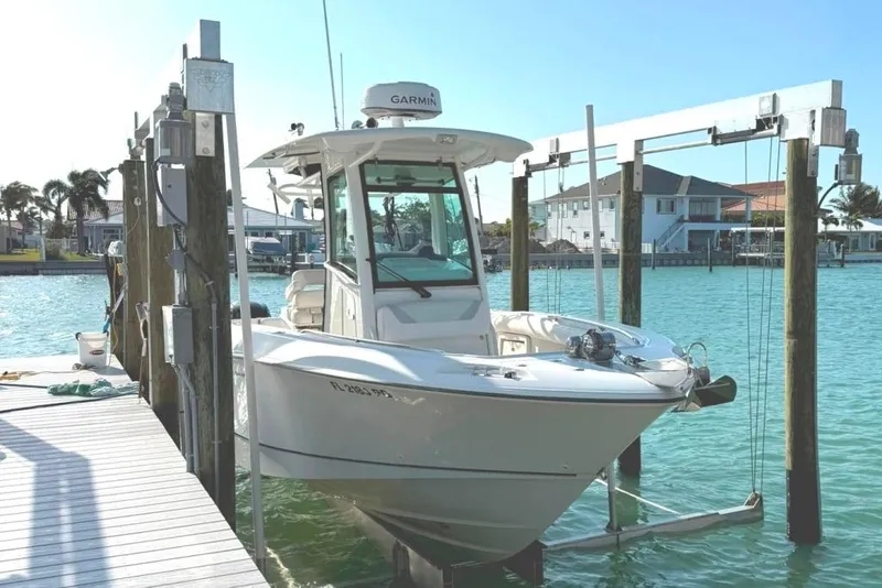 The Image of 2012 Boston Whaler 250 Outrage boat docked on a sunny waterfront. - 1