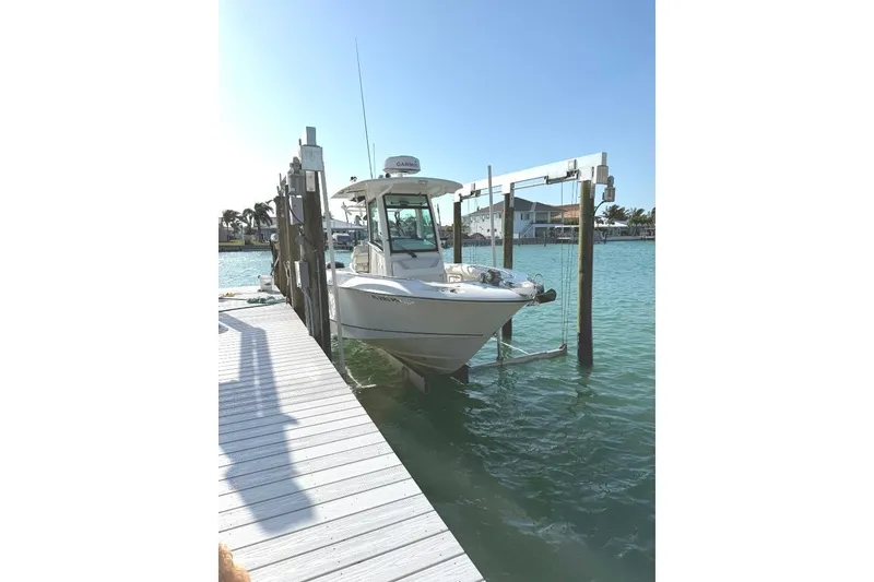 Slide: The Image of 2012 Boston Whaler 250 Outrage boat docked on a lift in sunny marina. - 2