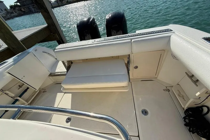 Slide: The Image of 2012 Boston Whaler 250 Outrage boat interior with seating and storage, docked by the water. - 22