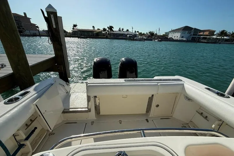 Slide: The Image of 2012 Boston Whaler 250 Outrage boat docked, featuring dual engines and spacious deck. - 25