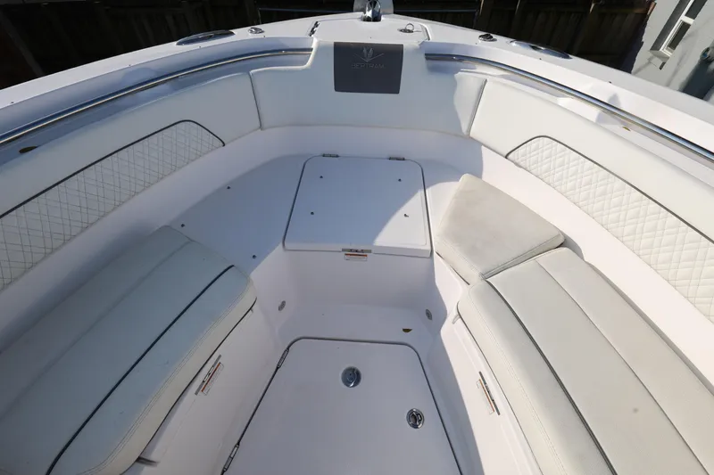 Slide: The Image of 2023 Bertram 28 CC boat interior with white cushioned seating and storage compartments. - 18