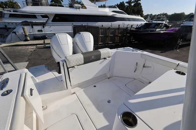 Slide: The Image of 2023 Bertram 28 CC boat with dual Mercury engines, docked near luxury yachts. - 24