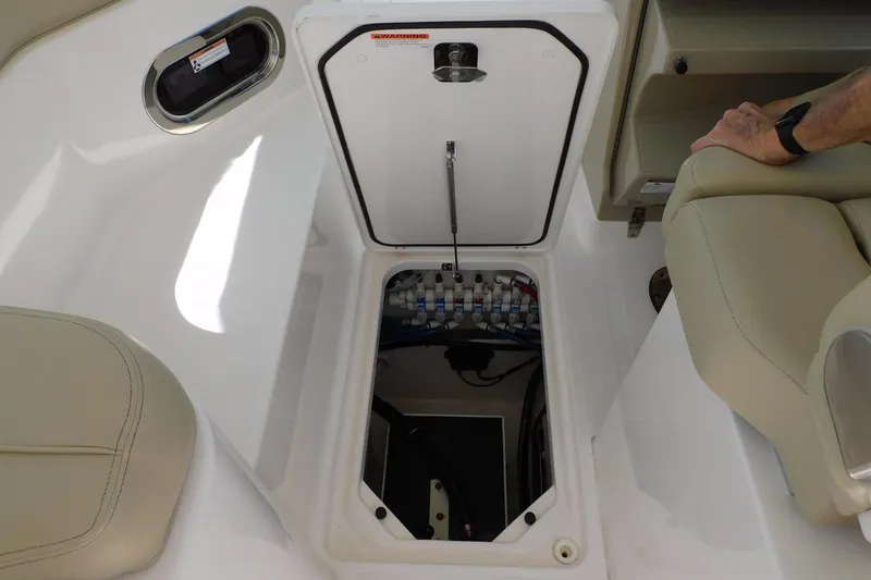 Slide: The Image of 2016 Pursuit DC 325 Dual Console boat storage compartment with open hatch and visible wiring. - 23