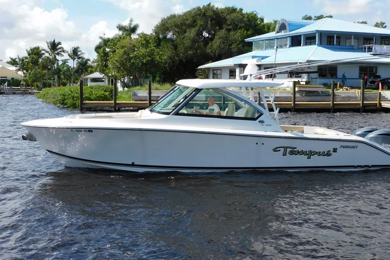 Slide: The Image of 2016 Pursuit DC 325 Dual Console boat on water near a dockside house. - 38