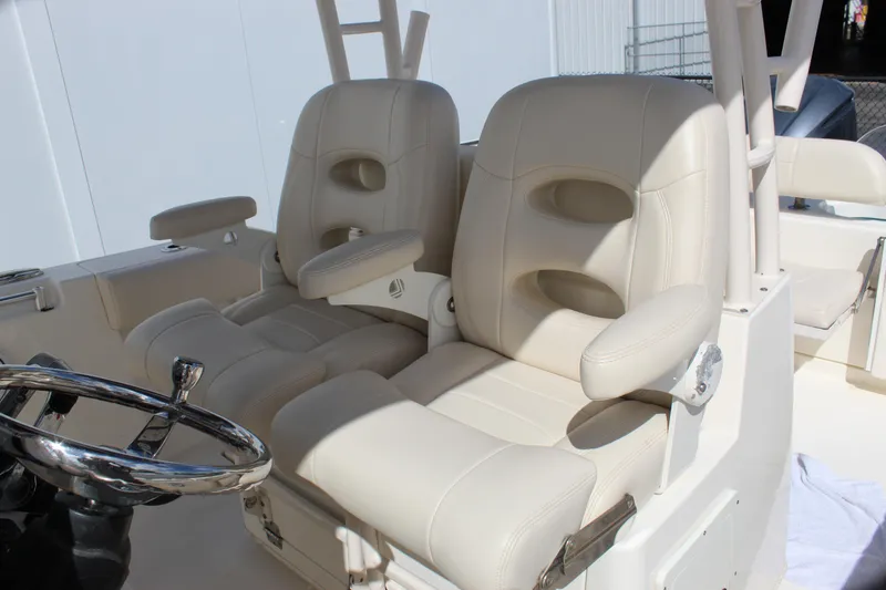 Slide: The Image of 2019 Cobia 301 Center Console boat with beige captain seats and steering wheel. - 24