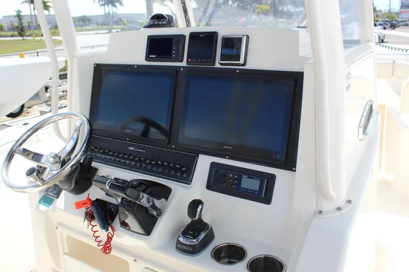 Slide: The Image of 2019 Cobia 301 Center Console boat dashboard with dual screens and steering wheel. - 29