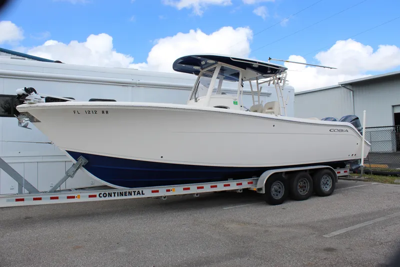 Slide: The Image of 2019 Cobia 301 Center Console boat on trailer, parked outdoors. - 4