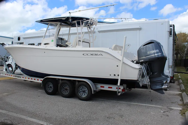 Slide: The Image of 2019 Cobia 301 Center Console boat on trailer with Yamaha engine, parked outdoors. - 6